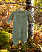 Last inn bildet i Galleri-visningsprogrammet, Hans babydress er en søt dress med perlestrikket bord på bærestykket. 
Dressen strikkes ovenfra og ned med raglanøkninger. En enkel og stilfull babydress som passer til både jenter og gutter. Baksiden av Babydressen.
