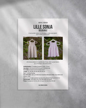 Last inn bildet i Galleri-visningsprogrammet, En søt og tidløs selekjole med blondekant i midjen og på skjørtet.
Kjolen strikkes ovenfra og ned. Forside av strikkeoppskrift.