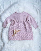 Last inn bildet i Galleri-visningsprogrammet, Sonja Finkjole strikkes nedenfra og opp i et gjentagende mønster over 5 omganger som gir et klassisk og tidløst uttrykk. Kjolen er inspirert av Sonja Dåpskjole og er en fin søskenmatch.