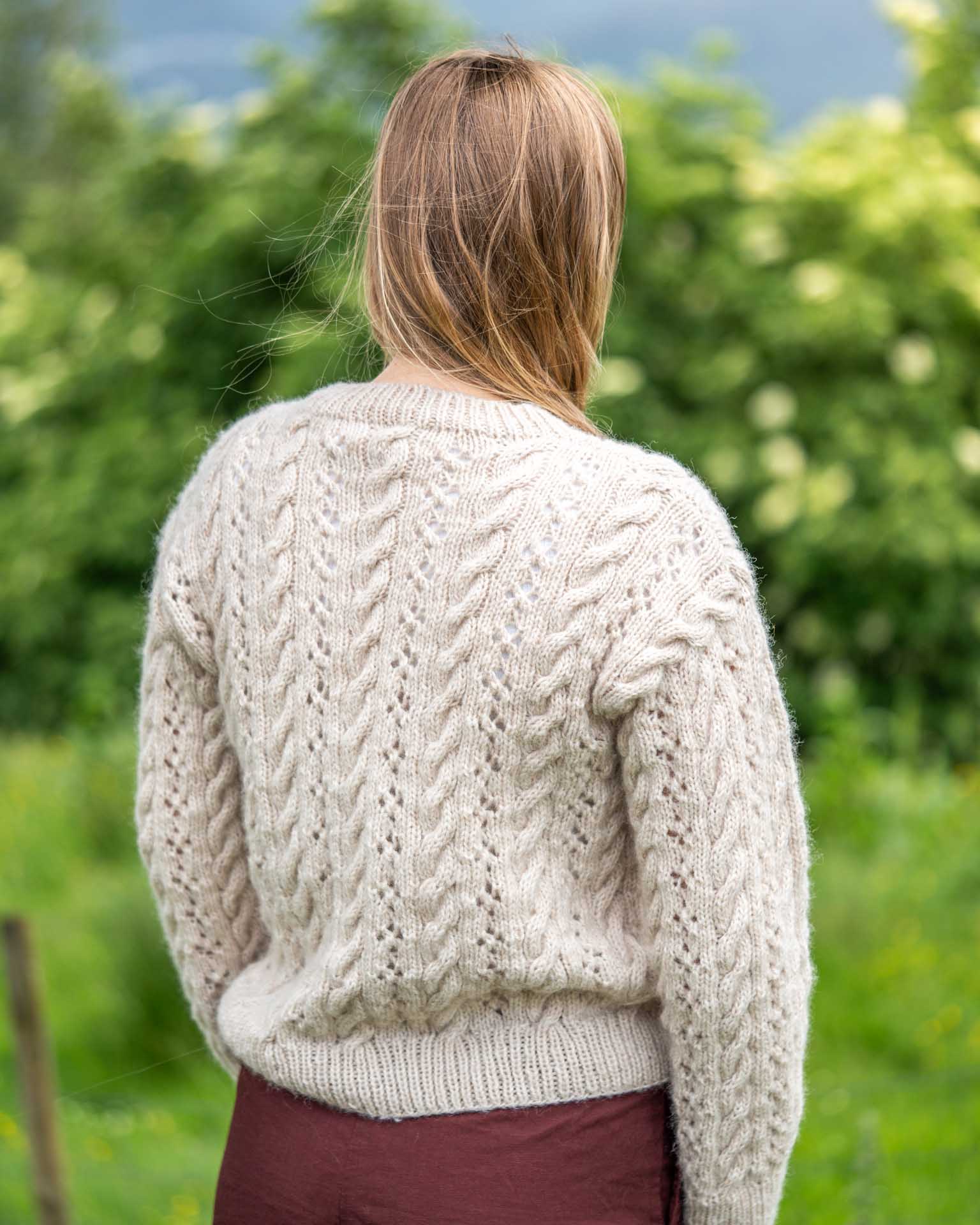 En lekker strukturstrikket genser med fletter og hullmønster. Like fin til jeans som over sommerkjolen. Genseren strikkes nedenfra og opp og det plukkes opp masker til ermene som strikkes ovenfra og ned. Baksiden av genseren.