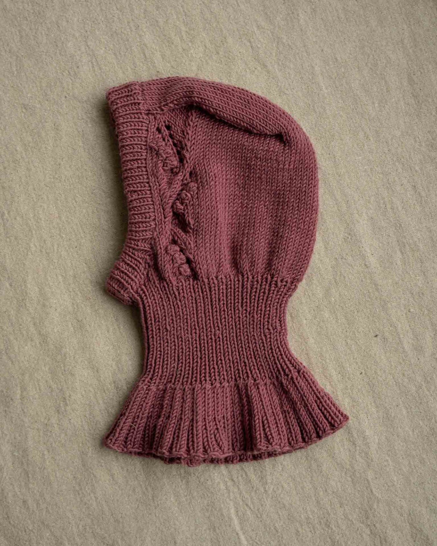 Helga Balaclava er en søt lue med nydelig struktur på begge sidene av luen. Balaklavaen strikkes ovenfra og ned. Kilen strikkes først før det plukkes opp masker langs sidene av denne. Videre strikkes det frem og tilbake med mønster før det økes til hals som strikkes rundt. Det økes deretter masker som danner en kappe rundt skuldre, rygg og bringe. Til slutt plukkes det opp masker og strikkes kant rundt ansiktsåpningen på hetten.