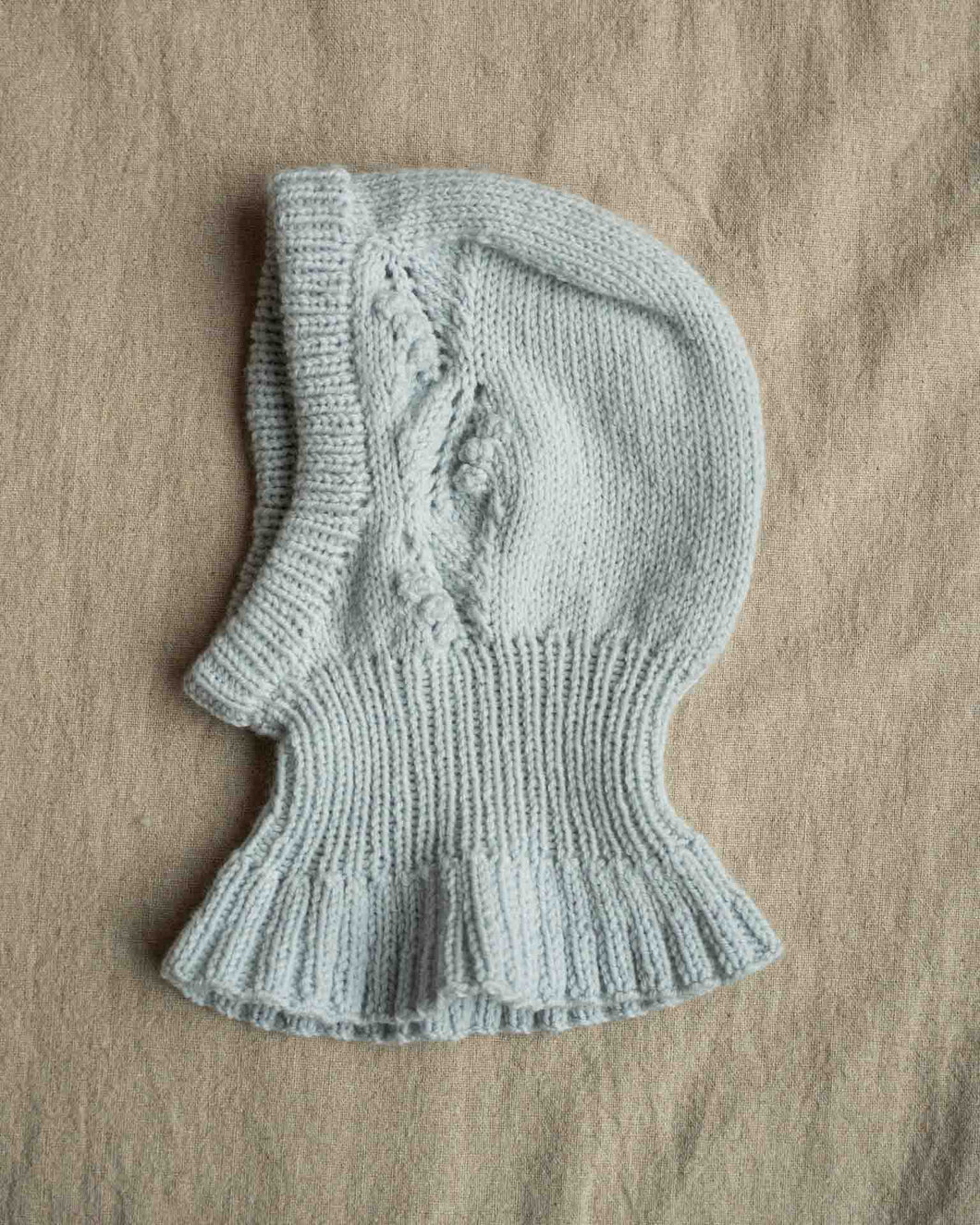 Helga Balaclava er en søt lue med nydelig struktur på begge sidene av luen. Balaklavaen strikkes ovenfra og ned. Kilen strikkes først før det plukkes opp masker langs sidene av denne. Videre strikkes det frem og tilbake med mønster før det økes til hals som strikkes rundt. Det økes deretter masker som danner en kappe rundt skuldre, rygg og bringe. Til slutt plukkes det opp masker og strikkes kant rundt ansiktsåpningen.