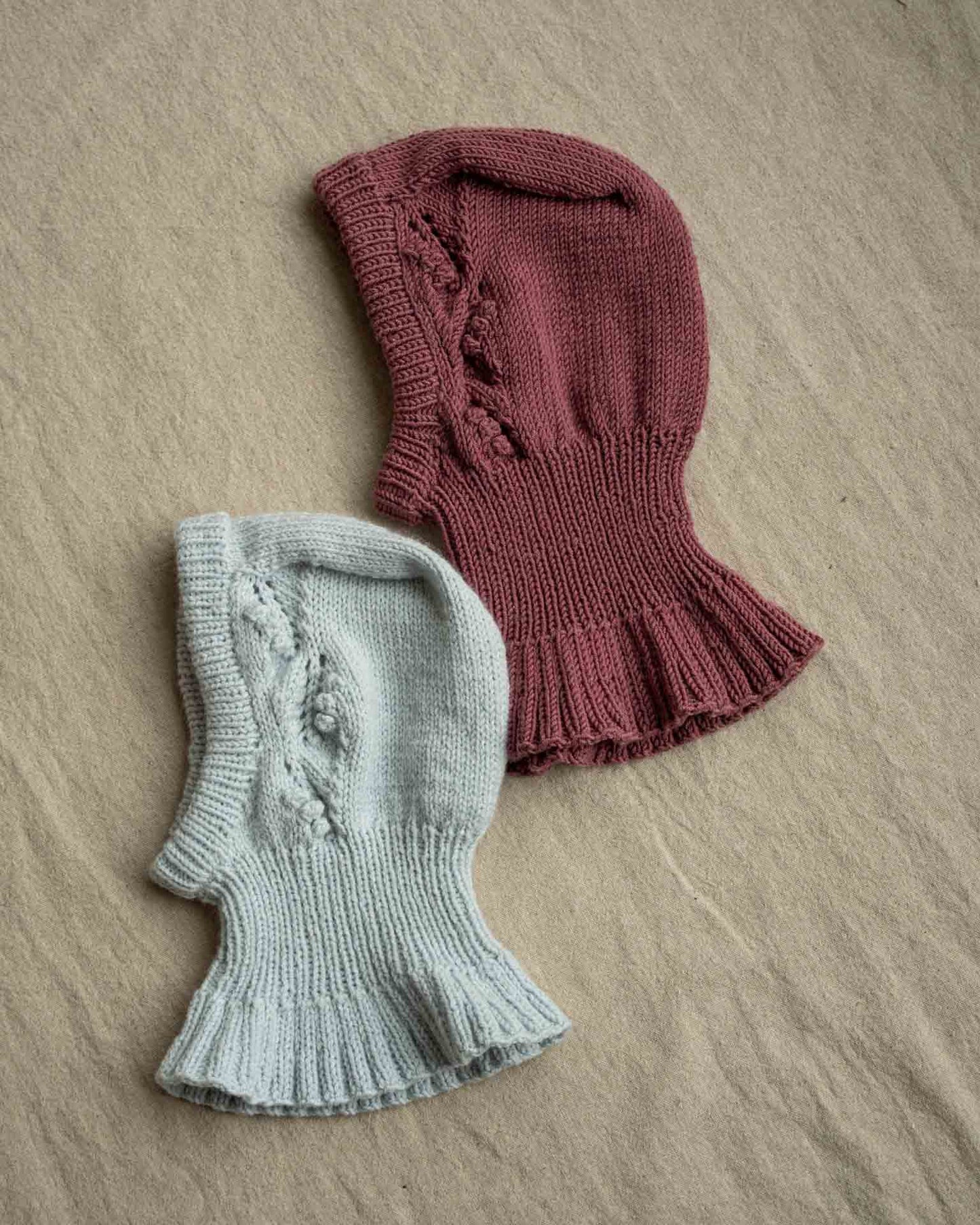 Helga Balaclava er en søt lue med nydelig struktur på begge sidene av luen. Balaklavaen strikkes ovenfra og ned. Kilen strikkes først før det plukkes opp masker langs sidene av denne. Videre strikkes det frem og tilbake med mønster før det økes til hals som strikkes rundt. Det økes deretter masker som danner en kappe rundt skuldre, rygg og bringe. 