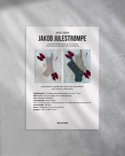 Last inn bildet i Galleri-visningsprogrammet, Julestrømpen strikkes ovenfra og ned i et nydelig strukturmønster bestående av fletter og hullmønster. Forside av strikkeoppskrift.
