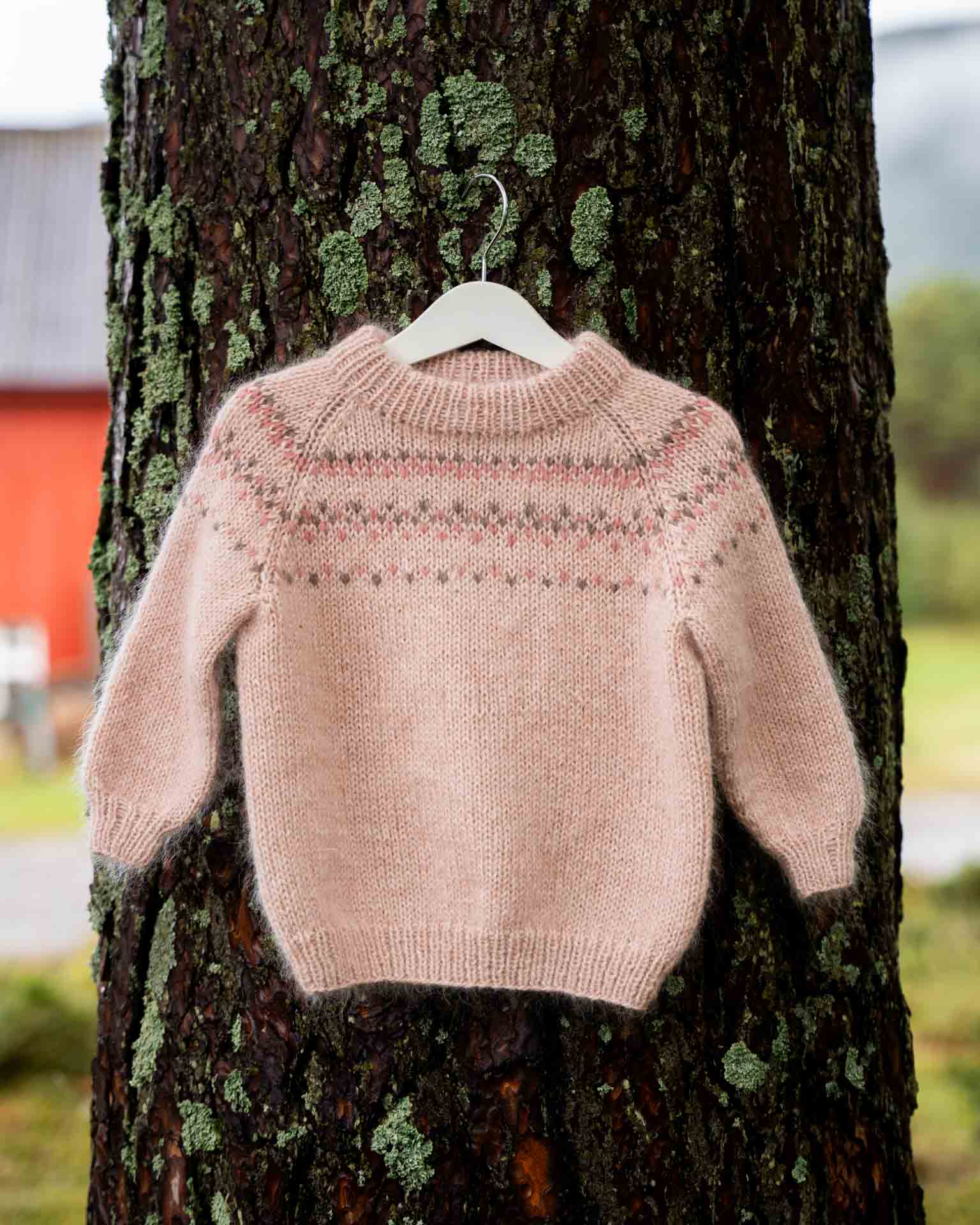 En myk og deilig genser som strikkes nedenfra og opp med raglanfellinger.
Genseren strikkes i dobbelt eller trippelt garn med  et lekkert mønster. Her i en nydelig rosafarge for jenter.