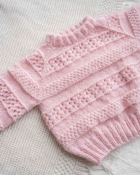 En søt genser i en blanding av mohair, silke og merinoull. Den er strukturstrikket med hullmønster og dobbel perlestrikk. Kommer i størrelse til barn og dame og er en nydelig mamma og mini-match.