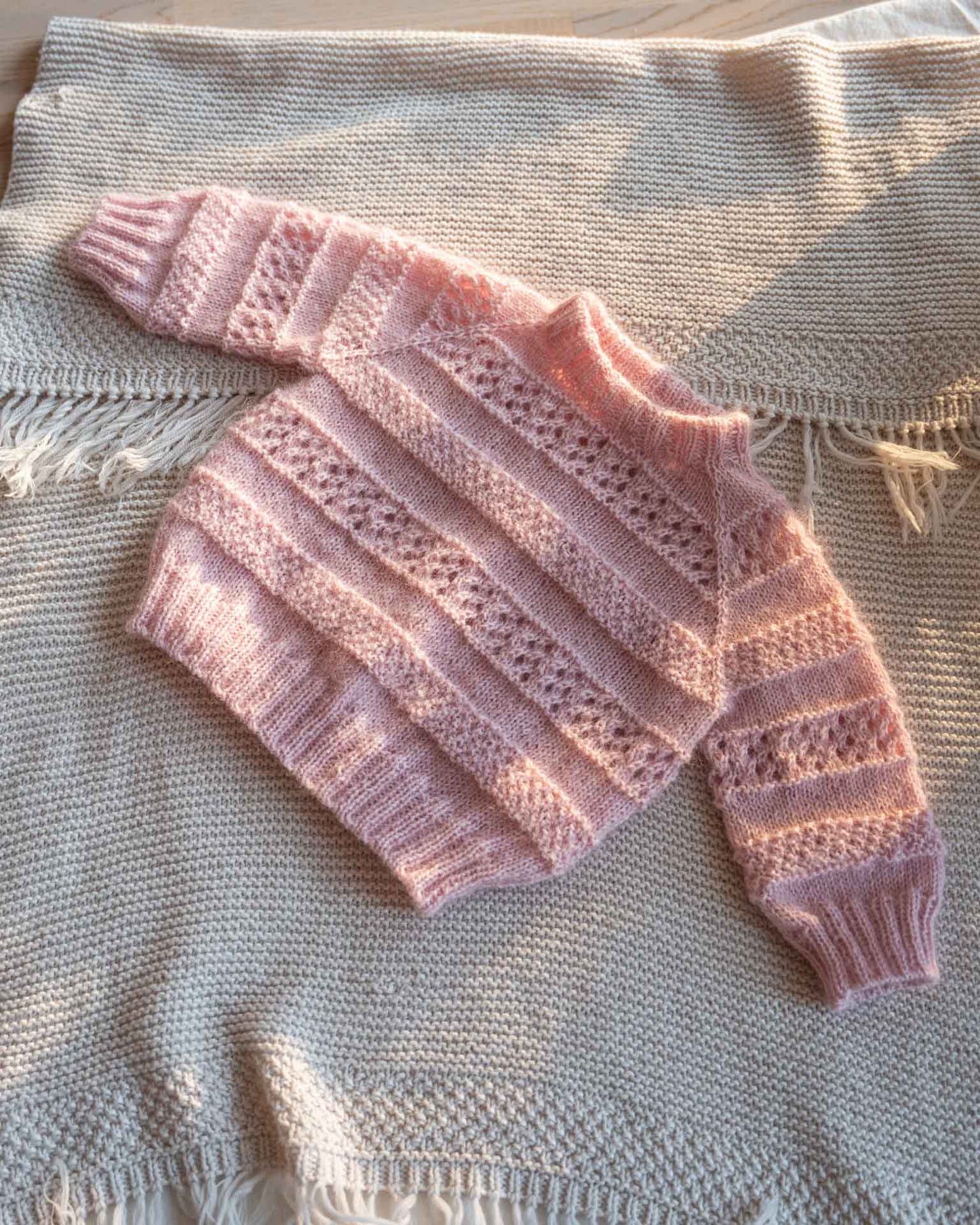 Karen Sweater er en søt genser strukturstrikket med hullmønster og dobbel perlestrikk. Kommer i størrelse til barn og dame og er en nydelig mamma og mini match, og mama og me.