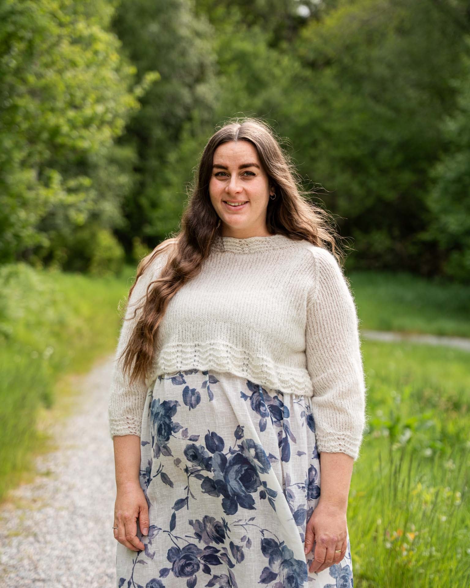 Karoline Bluse er en lett og luftig genser med trekvart ermer, den strikkes nedenfra og opp og kan strikkes kort eller lang. Strikket i Rauma Alpakka Lin garn.