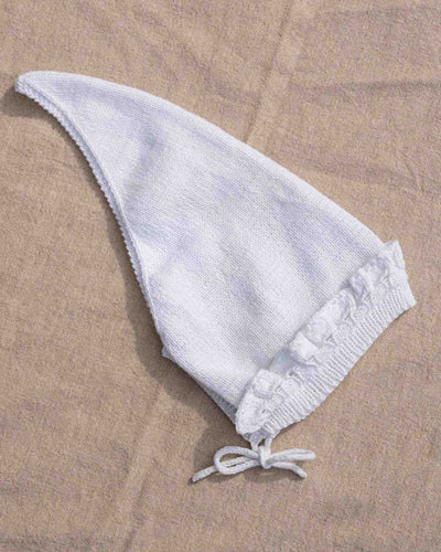 Et tidløst og søtt skaut med blondekant rundt ansiktet. Hele skautet strikkes frem og tilbake. Det plukkes opp masker til halskant, og til blondekant rundt ansiktet.