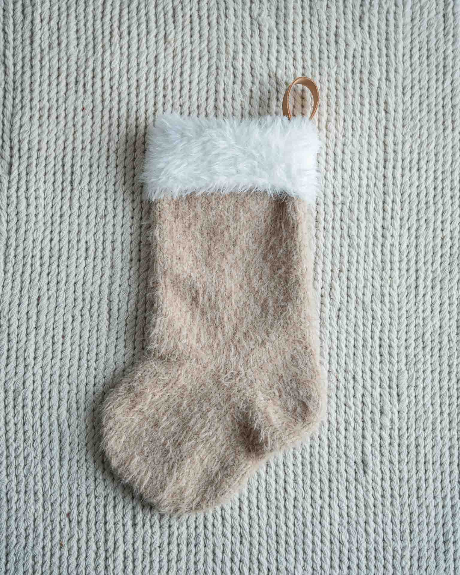 Mons julestrømpe er en klassisk julestrømpe med pelskant og skinnhempe. 
Julestrømpen kommer i tre ulike størrelser og har god hold slik at den henger pent. I trendy beige farge.