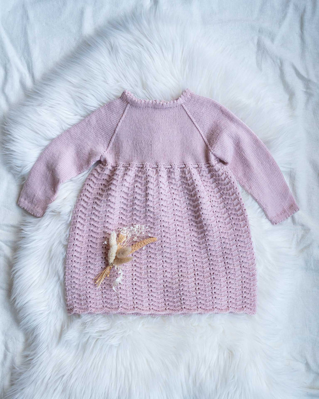 Sonja Finkjole strikkes nedenfra og opp i et gjentagende mønster over 5 omganger som gir et klassisk og tidløst uttrykk. Kjolen er inspirert av Sonja Dåpskjole og er en fin søskenmatch.