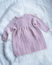 Last inn bildet i Galleri-visningsprogrammet, Kjolen strikkes nedenfra og opp i et gjentagende mønster over 5 omganger som gir et klassisk og tidløst uttrykk. Kjolen har knytting rundt livet, og er en søt kjole for barn.
