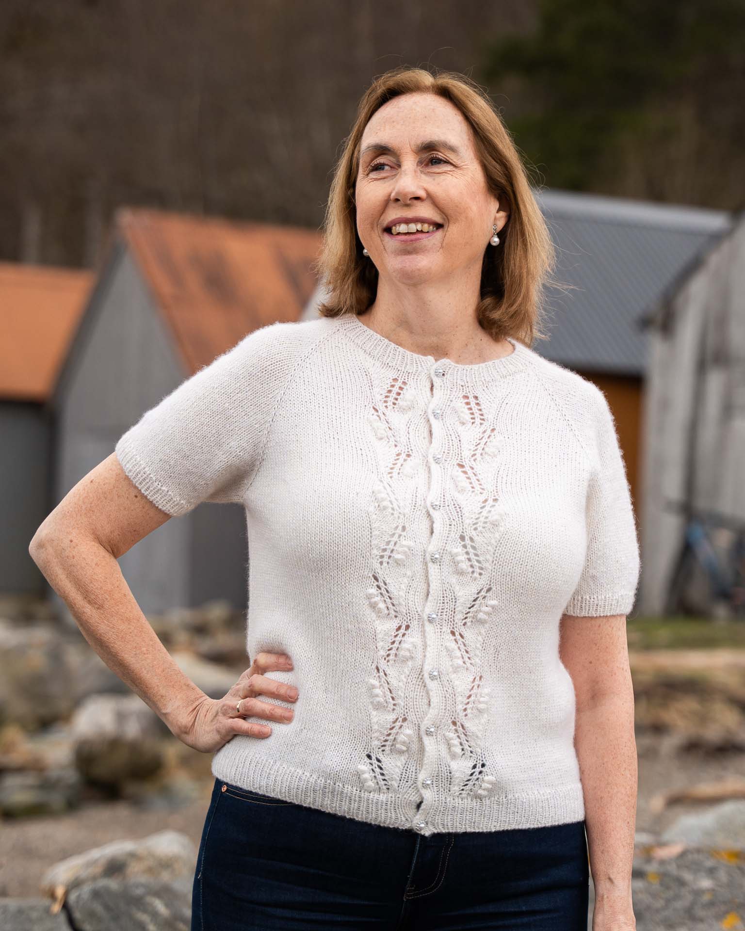 Helga Kortermet Cardigan er en lekker og stilren sommertopp med struktur på fremsiden. Den strikkes ovenfra og ned med to tråder, halsutringingen dannes ved vendepinner og stolpen strikkes i vrangbord samtidig som resten av arbeidet.