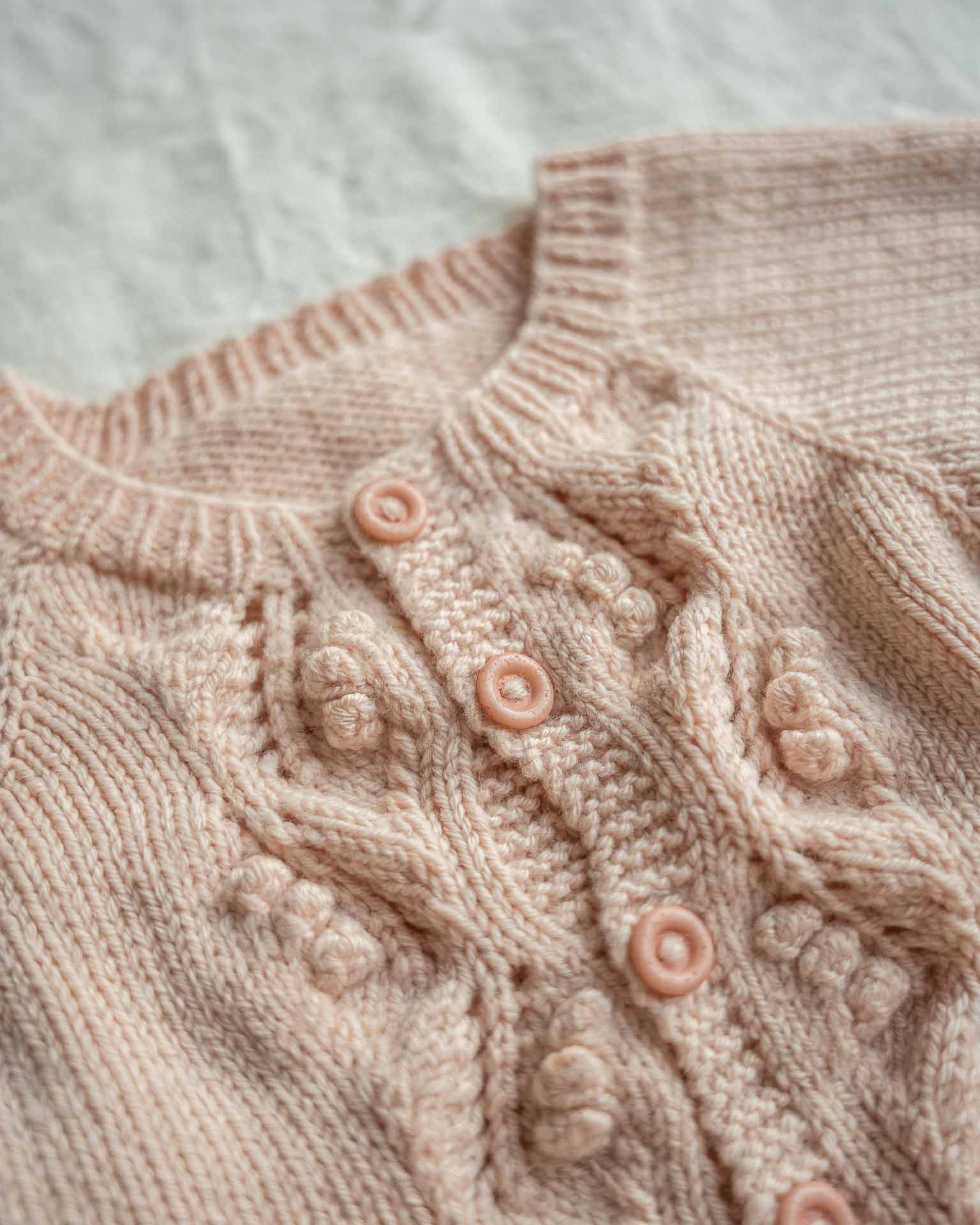 Helga babydress er en søt dress med struktur på fremsiden. Nærbilde av struktur og knapper.