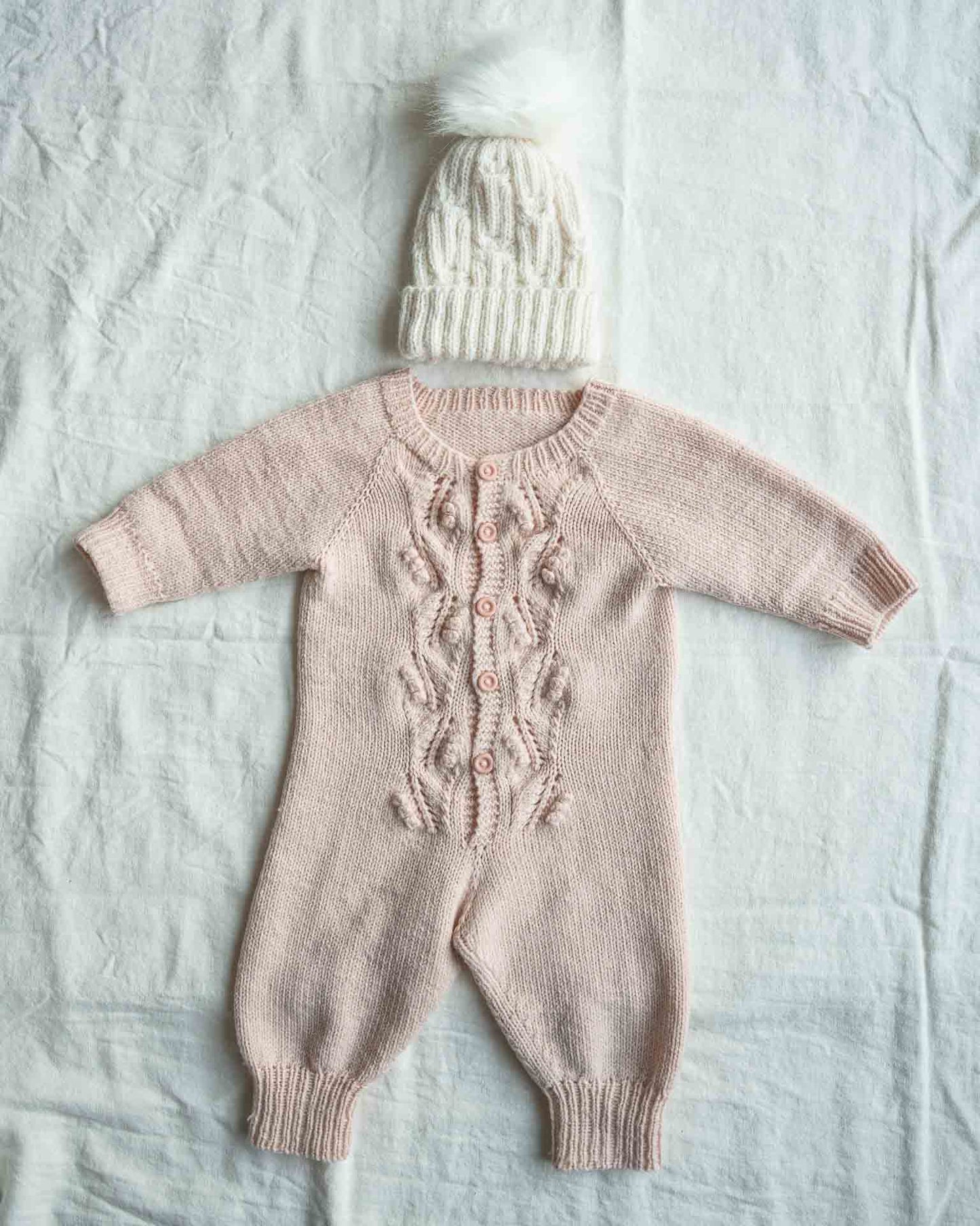 Helga babydress er en søt dress med struktur på fremsiden. Strikkedressen strikkes ovenfra og ned. Her i en flott beige farge.