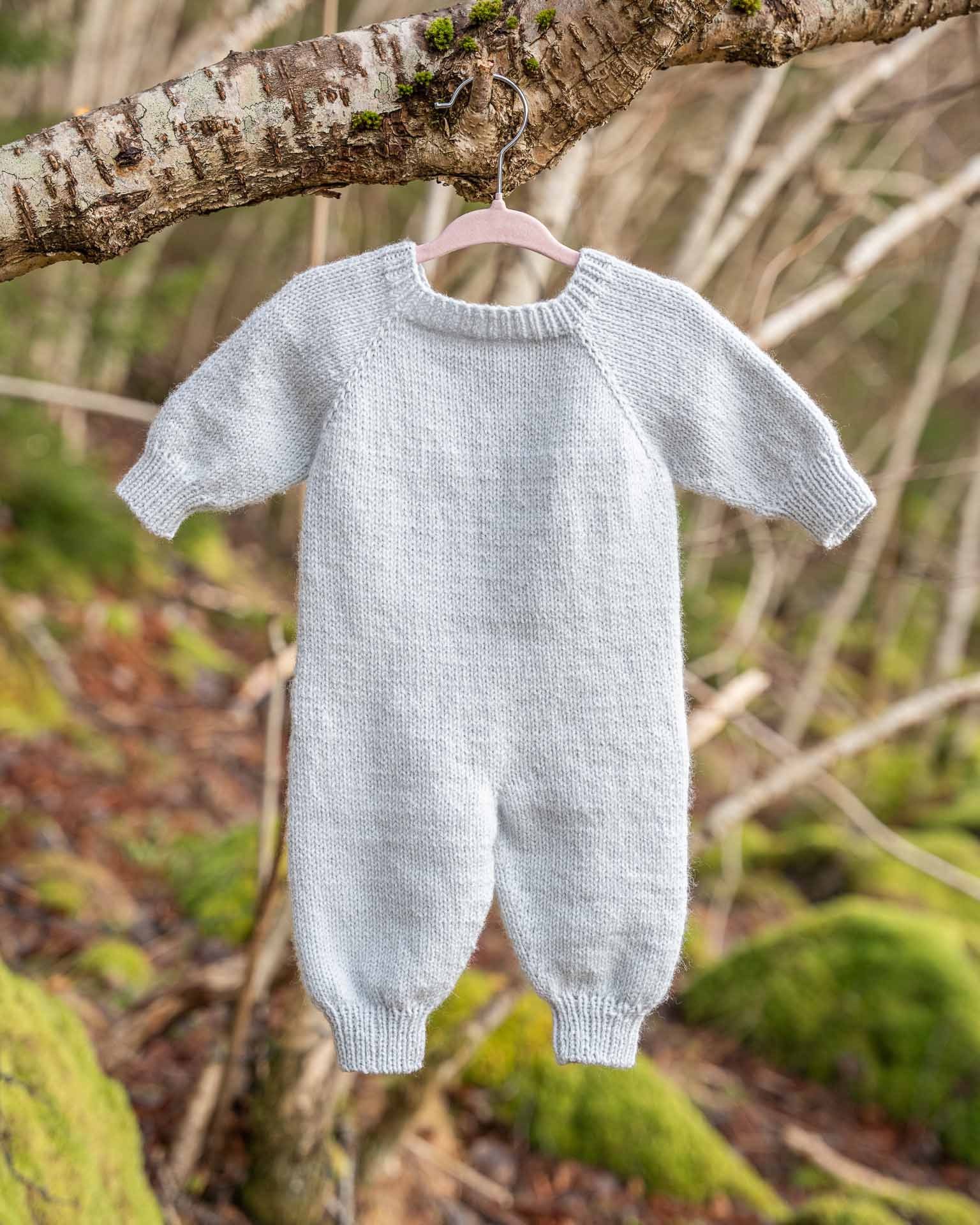 Helga babydress er en søt dress med struktur på fremsiden. Dressen strikkes ovenfra og ned, halsutringingen dannes ved vendepinner og stolpen strikkes i riller samtidig som resten av arbeidet. I en søt blåfarge. Baksiden.