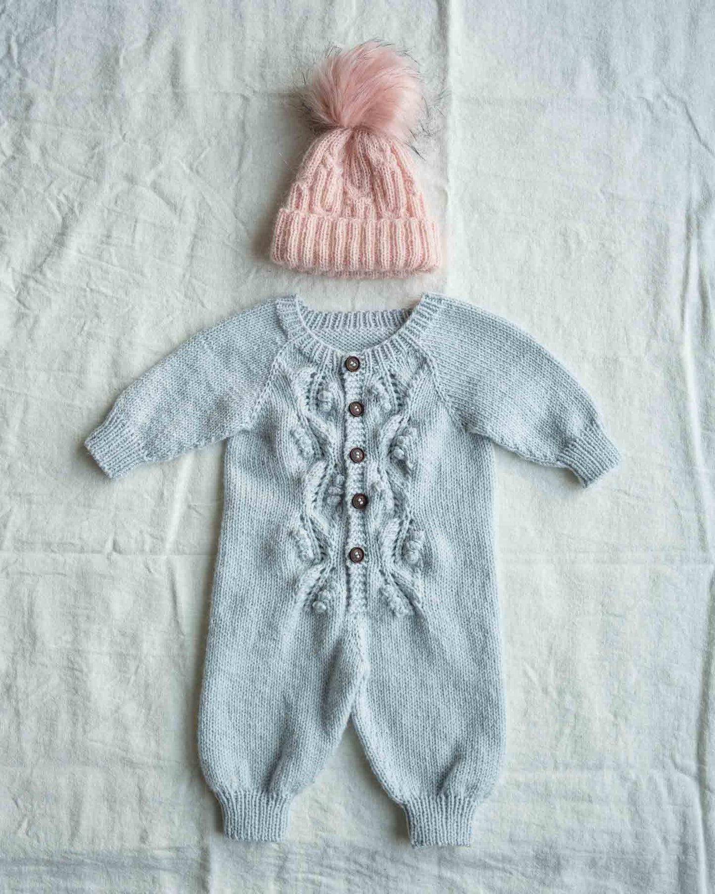Helga babydress er en søt dress med struktur på fremsiden. Dressen strikkes ovenfra og ned, halsutringingen dannes ved vendepinner og stolpen strikkes i riller samtidig som resten av arbeidet. Strikkedressen passer til både jenter og gutter. Her i en blå farge og med lue.